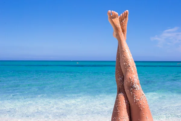 Closeup of female legs background of the turquoise sea — Stock Photo, Image