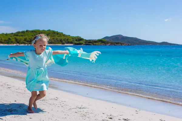 Glückliches kleines Mädchen läuft mit blauem Handtuch am Strand entlang — Stockfoto