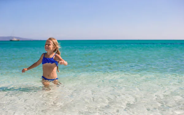 Adorável menina se divertir na praia tropical em águas rasas — Fotografia de Stock