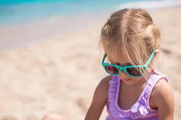 Schattig meisje spelen met zand op witte strand — Stockfoto