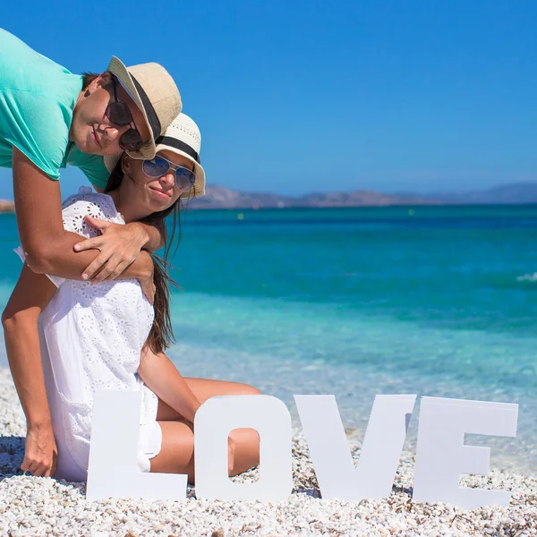 Giovane bella famiglia seduta sulla spiaggia con la parola Amore — Foto Stock