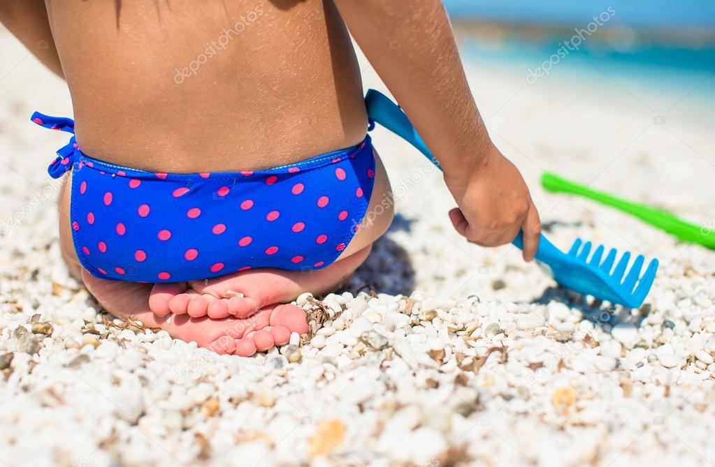 Closeup of little girl legs on tropical beach with toys