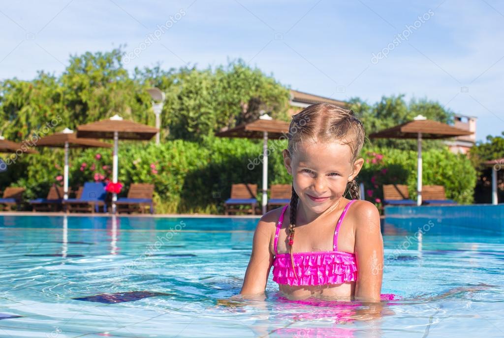 Cute happy little girl in the swimming pool looking at