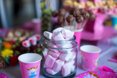 Hatmi, tatlı meringues, patlamış mısır, kremalı kek ve pasta renkli masaya açılır