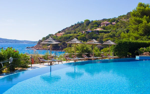 Deck chairs and infinity pool over amazing tropical lagoon — Stock Photo, Image