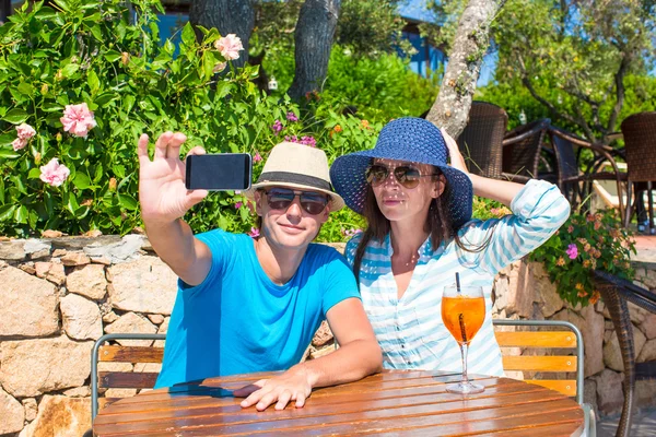 Young couple taking photo with smartphone in outdoor cafe — Stock Photo, Image