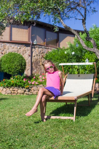 Happy little girl on beach lounger outdoors — Stock Photo, Image