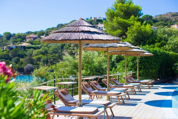 Chaises longues et parasols en bois près de la piscine à débordement dans un complexe de luxe — Photo