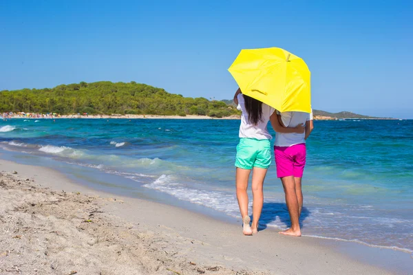 Vista trasera de pareja romántica en la playa blanca con paraguas amarillo — Foto de Stock