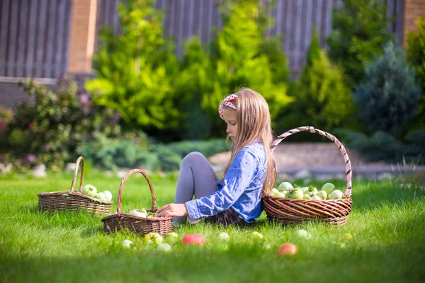 Adorable little girl with autumn harvest of tomato on the lawn — Stock Photo, Image