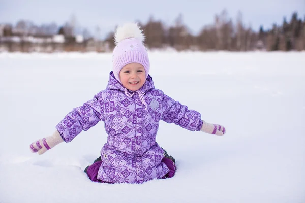 Little happy girl having fun on the snow at winter sunny day — Stock Photo, Image