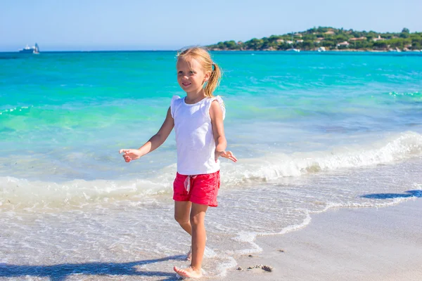 Adorable niña jugando en aguas poco profundas en la playa blanca —  Fotos de Stock