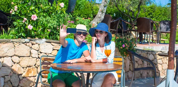 Young couple taking photo with smartphone in outdoor cafe