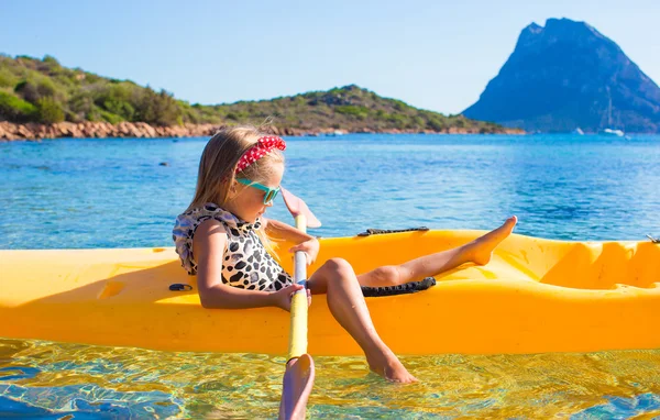 Little girl enjoying swimming in yellow kayak in the clear turquoise water — Stock Photo, Image