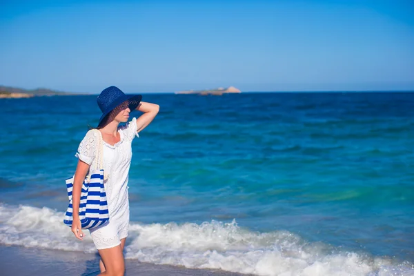 Krásná žena v klobouku a tašku na tropické pláži s bílým pískem — Stock fotografie