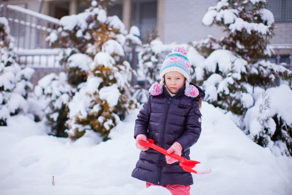 Little adorable girl play with snow shoveling on winter day — Stock Photo, Image