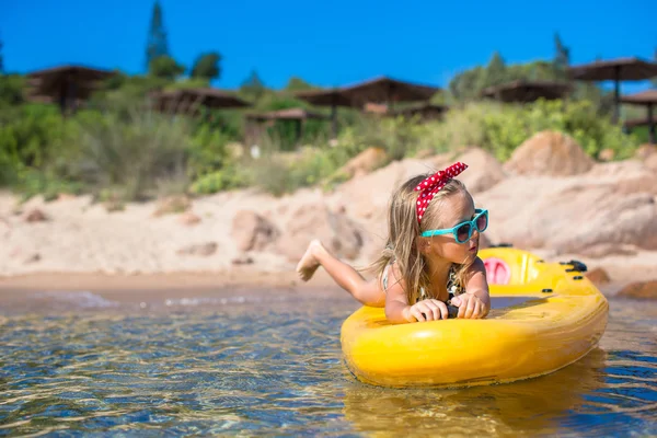 Niña linda disfrutando nadando en kayak amarillo en el agua turquesa transparente —  Fotos de Stock