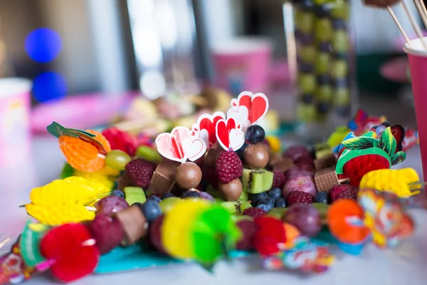 Canapé de frutas, pasteles de chocolate blanco y palomitas de maíz en la mesa de los niños dulces en la fiesta de cumpleaños —  Fotos de Stock