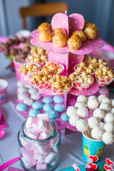 Marshmallow, doces merengues coloridos, pipocas, bolos de creme e bolos brancos pops na mesa festiva — Fotografia de Stock