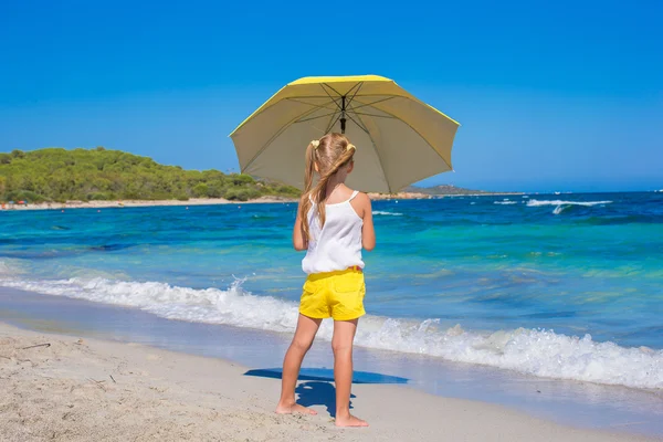 Vista trasera de niña con gran sombrilla caminando en la playa tropical — Foto de Stock