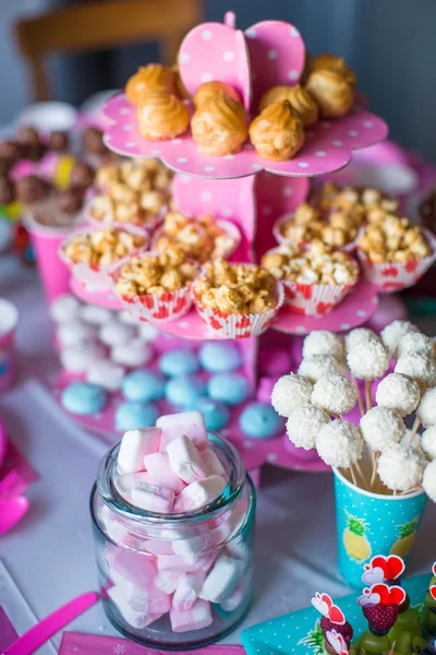 Hatmi, tatlı meringues, patlamış mısır, kremalı kek ve pasta beyaz renkli masaya açılır — Stok fotoğraf