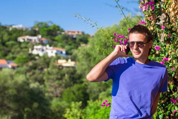 Young man talking on the phone at the balcony with beautiful view — Stock Photo, Image