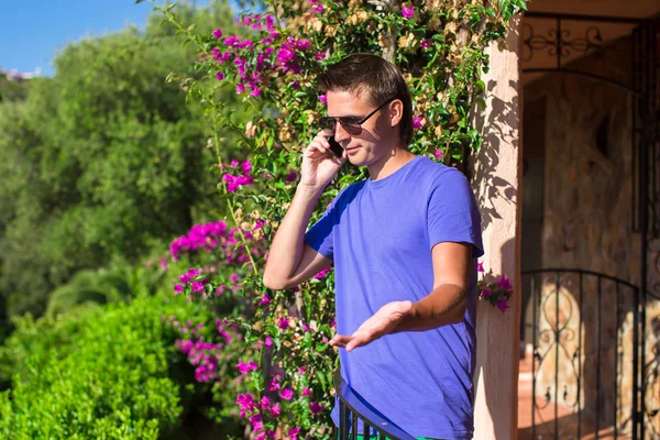 Young man talking on the phone at the balcony — Stock Photo, Image