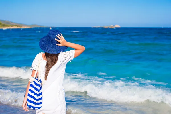 Menina com chapéu de palha e saco listrado azul na praia tropical — Fotografia de Stock