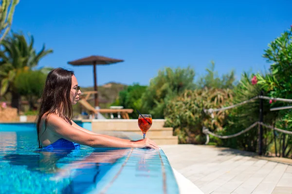 Beautiful young woman relaxing in swimming pool with cocktail — Stock Photo, Image