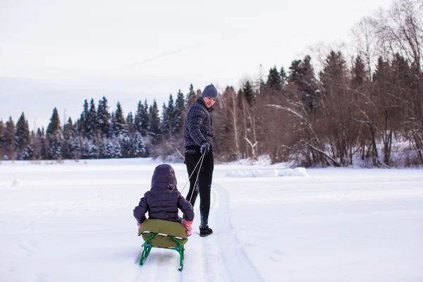 Young dad rolls his child on sledge in winter sunny day — Stock Photo, Image