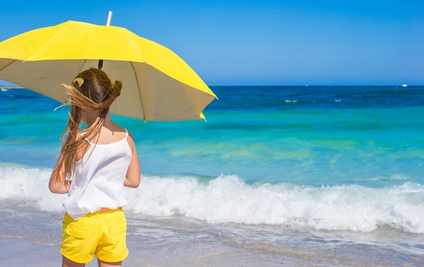 Menina com grande guarda-chuva amarelo andando na praia tropical — Fotografia de Stock