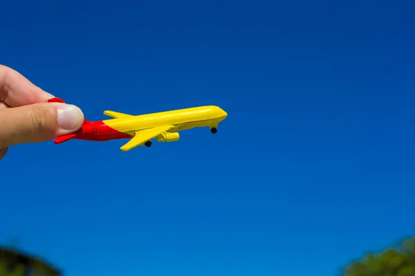 Pequeno avião na mão feminina no fundo do céu azul — Fotografia de Stock