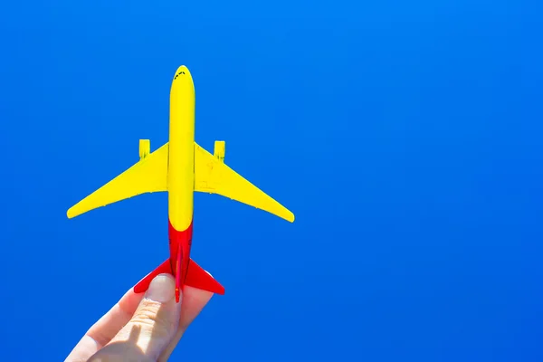 Petit avion à la main féminine sur fond de ciel bleu — Photo