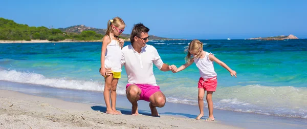 Padre joven e hijas pequeñas se divierten durante las vacaciones en la playa tropical — Foto de Stock