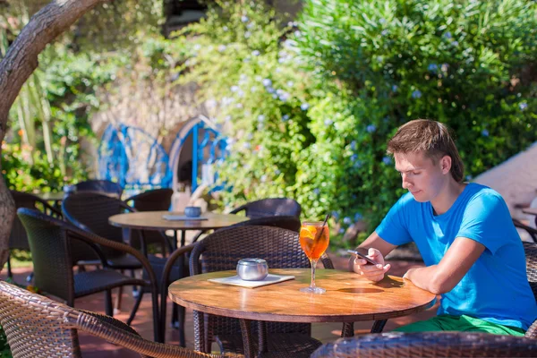 Young man in outdoor cafe talking on phone — Stock Photo, Image