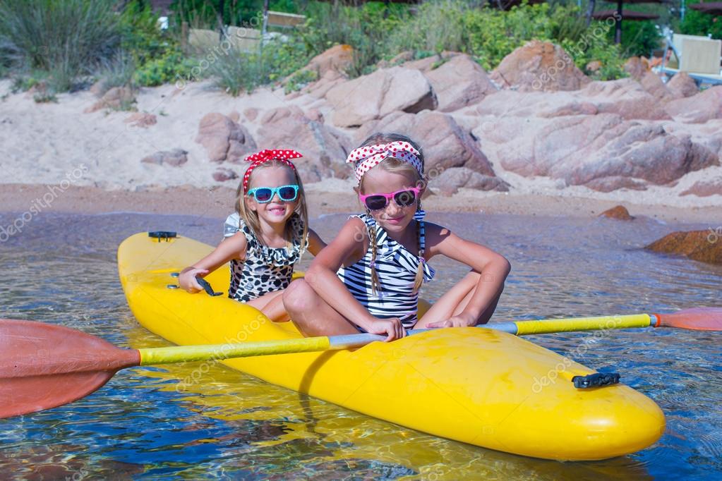 Little cute girls enjoying kayaking on yellow kayak in the clear