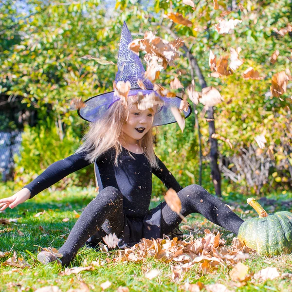 Rozkošná holčička v čarodějnice kostým vrhá kouzlo na halloween — Stock fotografie