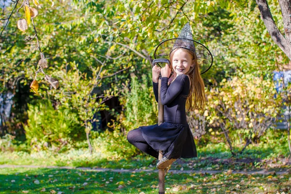 Rozkošná holčička v halloween čarodějnice kostým baví na koštěti — Stock fotografie