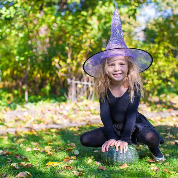 Rozkošná holčička v čarodějnice kostým vrhá kouzlo na halloween — Stock fotografie