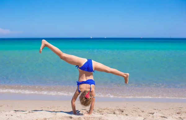 Adorável menina fazendo roda na praia de areia branca tropical — Fotografia de Stock