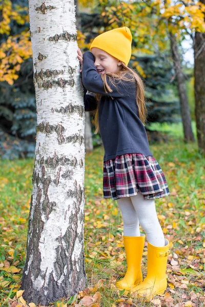 Menina brincando esconder e procurar na floresta de outono ao ar livre — Fotografia de Stock