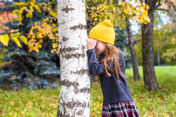 Meisje spelen verstoppertje in herfst bos buitenshuis — Stockfoto