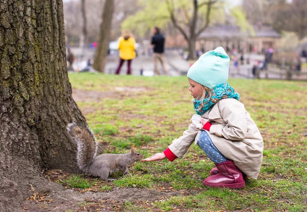 Little girl feeds a squirrel in Central park, New York, America — Stock Photo, Image