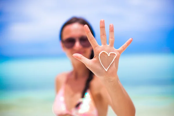 Крупный план руки девушки с сердцем на ладони, раскрашенной солнцезащитным кремом — стоковое фото