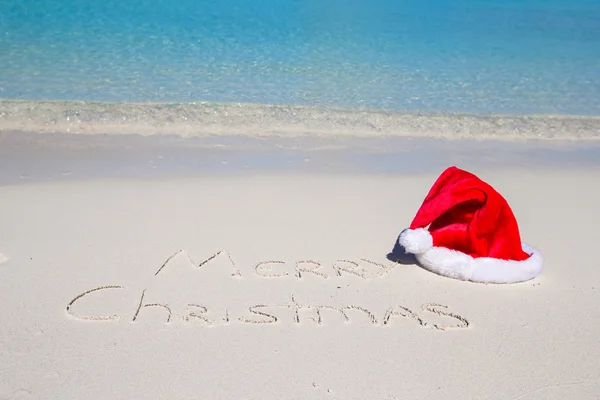 Vrolijk kerstfeest geschreven op tropisch strand wit zand met xmas hoed — Stockfoto