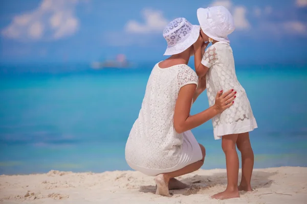 Jeune mère racontant un secret à l'oreille de sa petite fille — Photo