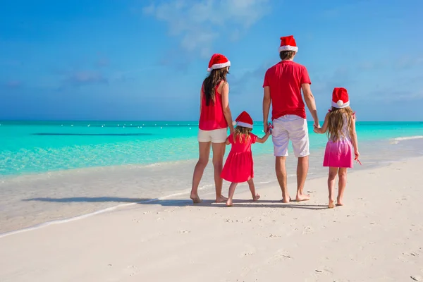 Gelukkige familie van vier in Kerstmis hoeden op witte strand — Stockfoto