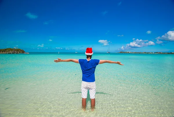 Jonge man in Kerstman hoed op tropisch strand — Stockfoto