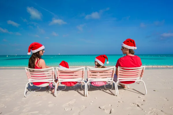 Glückliche vierköpfige Familie mit Weihnachtsmützen am weißen Strand — Stockfoto