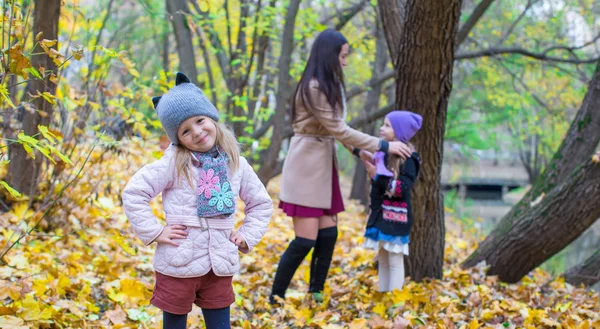 Kleine meisjes en jonge moeder in herfst park buiten — Stockfoto